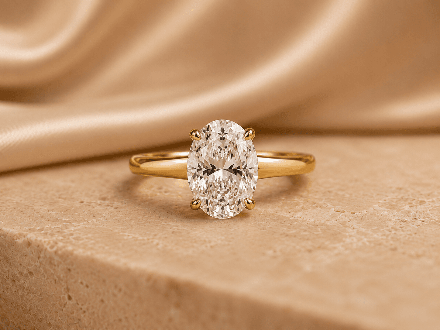 Oval diamond engagement ring in a classic yellow gold solitaire setting on a warm neutral surface